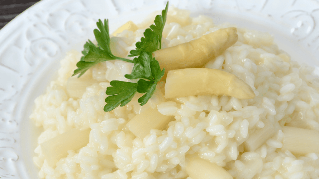 Risotto crémeux aux asperges blanches garni de persil.